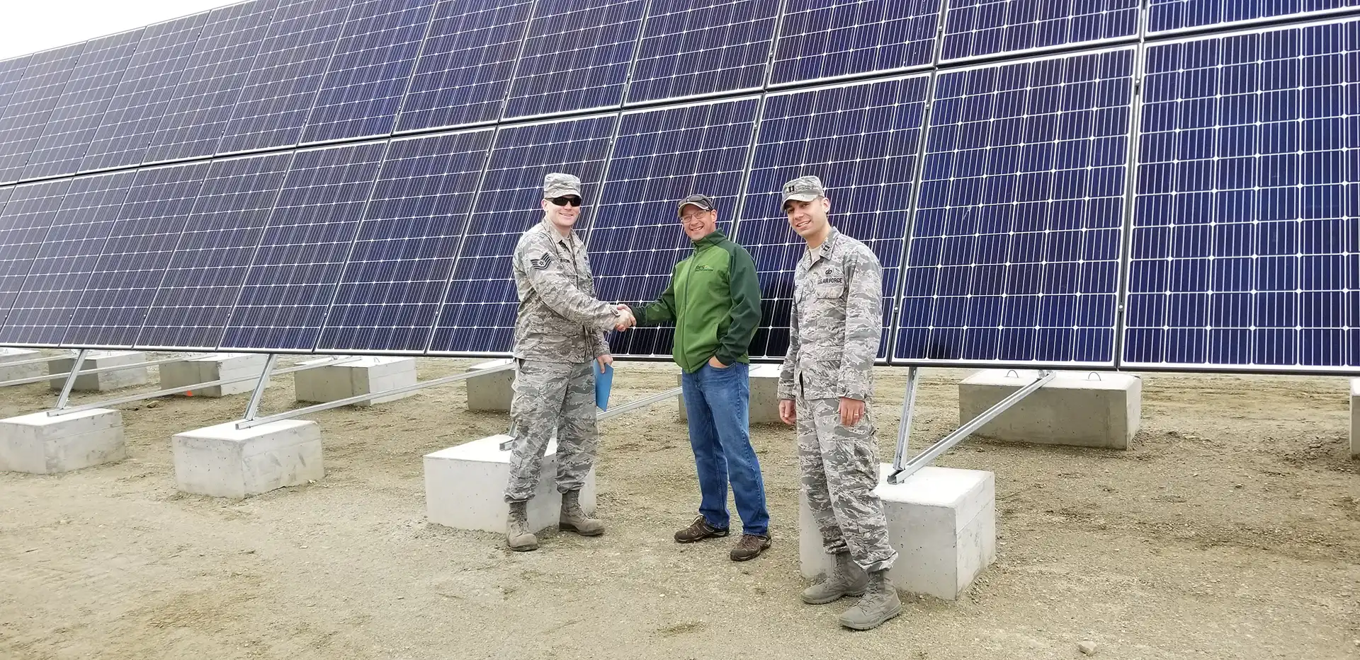 RES employee shakes hand with military contractors in front of solar panel