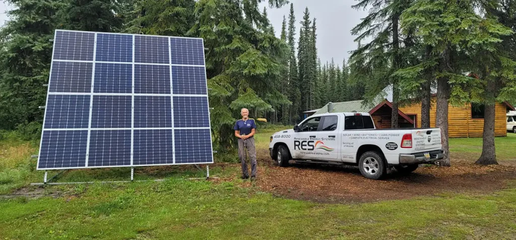 RES employee standing by completed solar installation in Alaska summer